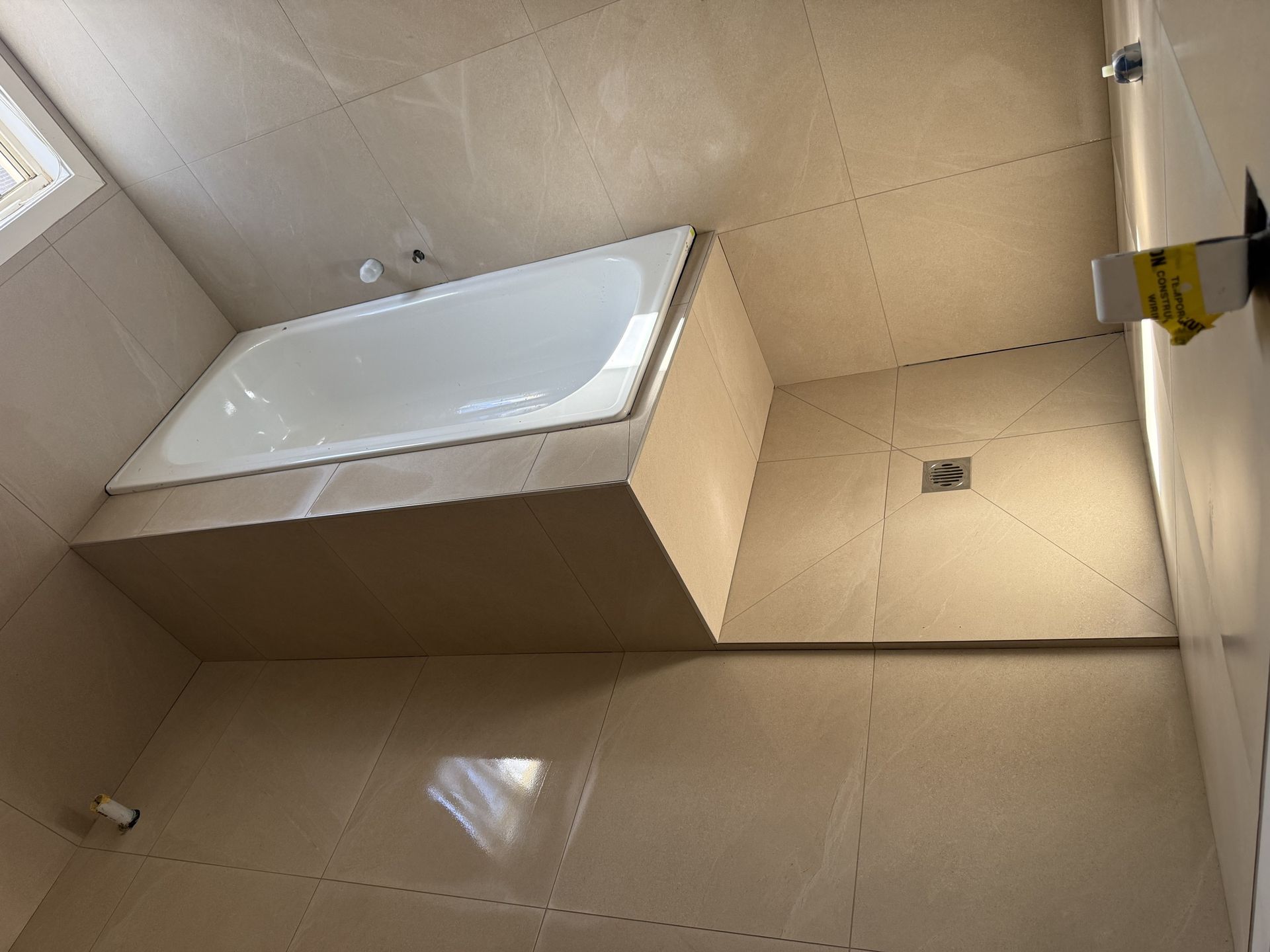 Bathroom tiling with bath surround and floor waste, set-out nearing completion